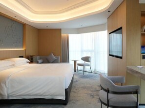 Une chambre d’hôtel avec un grand lit, un bureau, une chaise et un téléviseur.