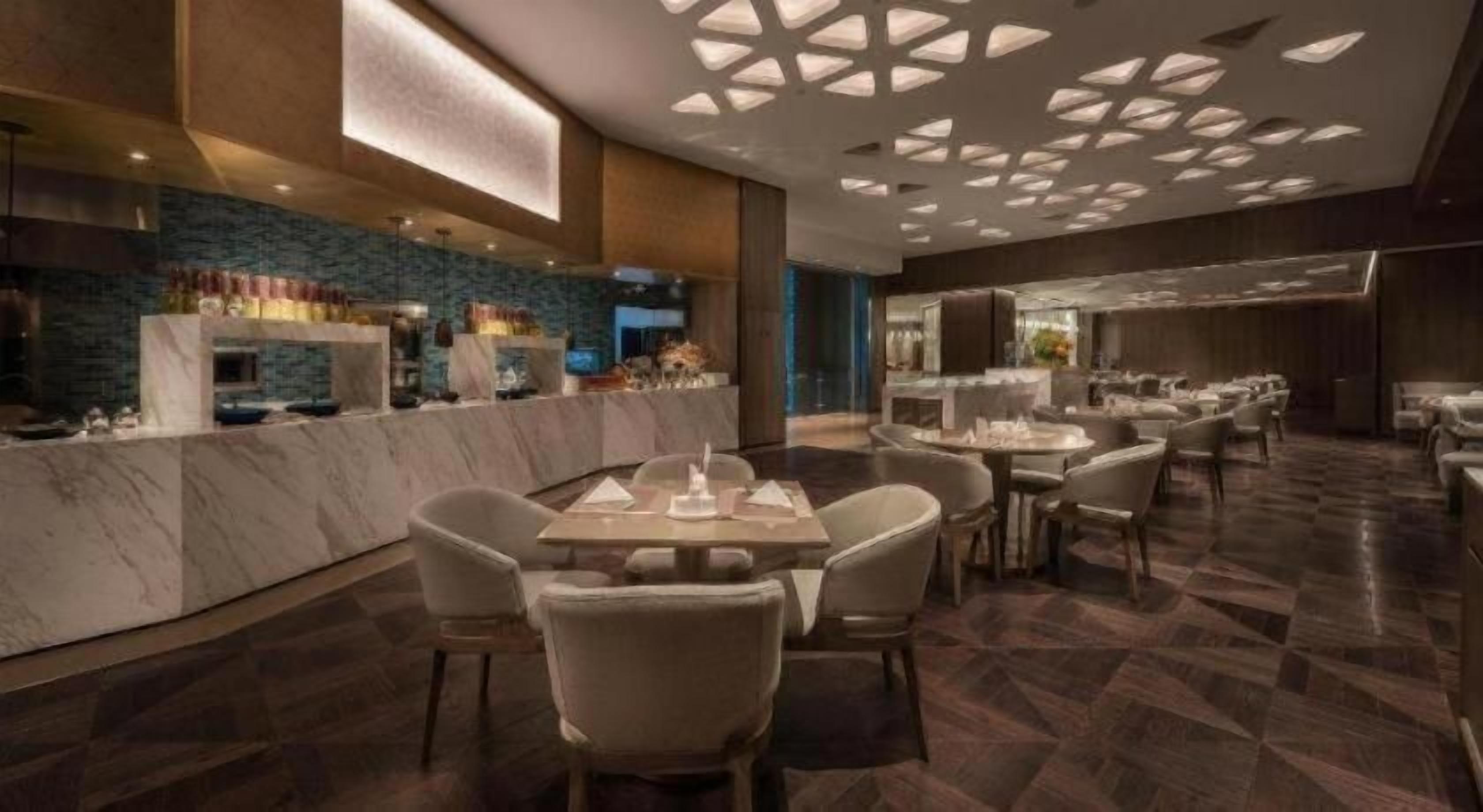 Un restaurant moderne doté de comptoirs en marbre, de nombreuses tables et d’un design de plafond original.