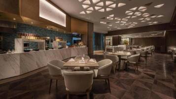Un restaurant moderne doté de comptoirs en marbre, de nombreuses tables et d’un design de plafond original.