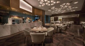 Un restaurant moderne doté de comptoirs en marbre, de nombreuses tables et d’un design de plafond original.