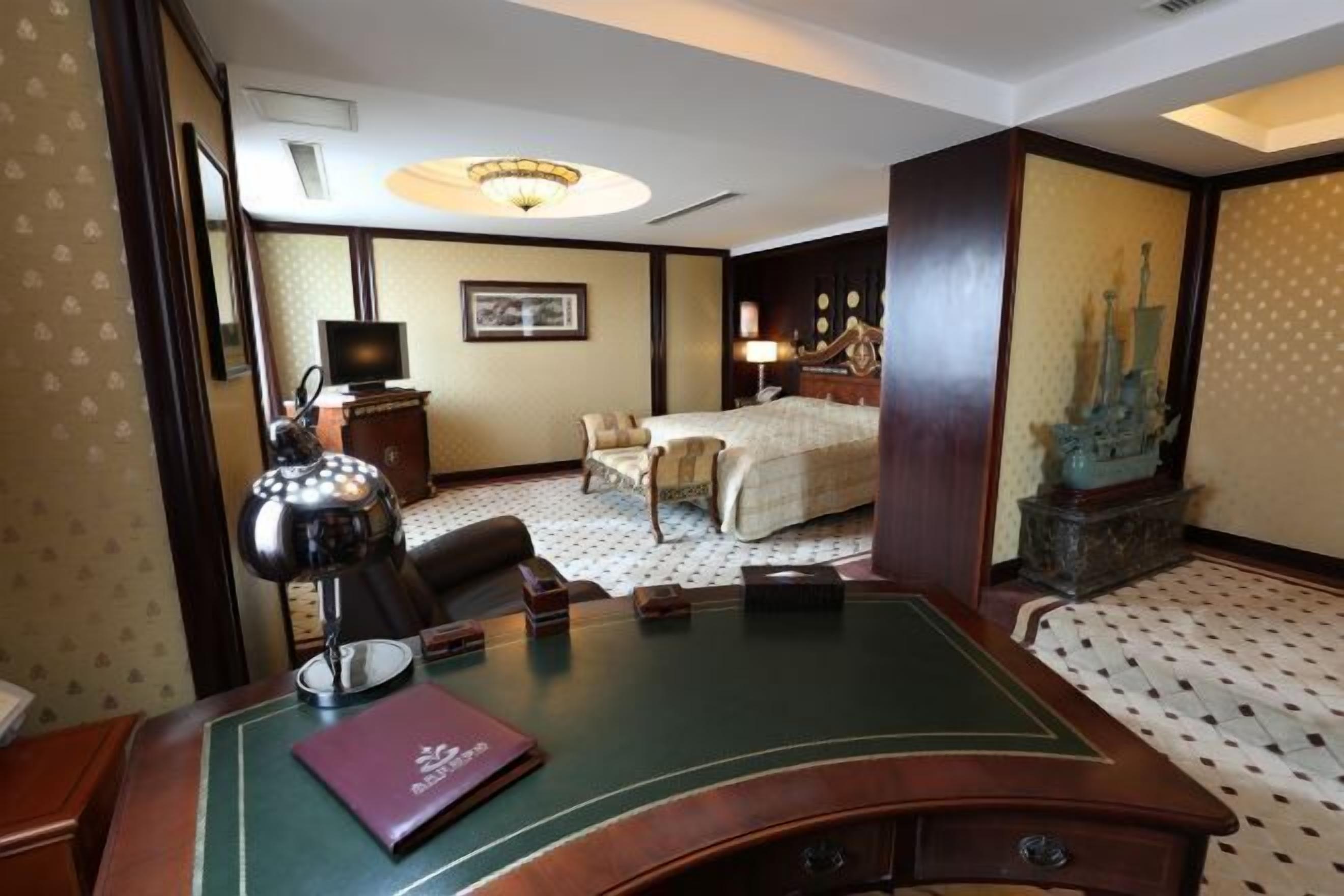 Ein Hotelzimmer mit Schreibtisch, einem Bett, einem Fernseher und einer Dekofigur.