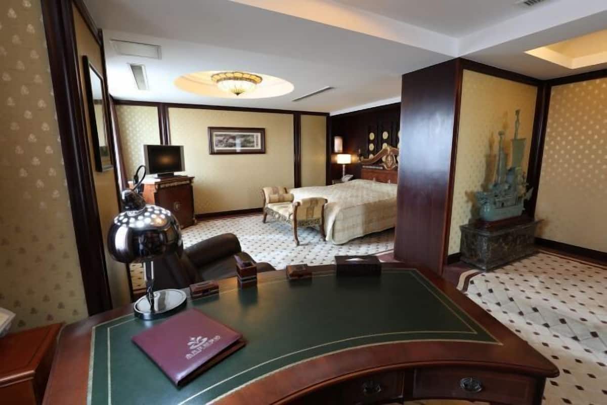 Ein Hotelzimmer mit Schreibtisch, einem Bett, einem Fernseher und einer Dekofigur.