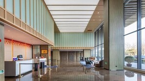 Un hall d’entrée spacieux avec un comptoir d’accueil, un espace salon et de grandes fenêtres.