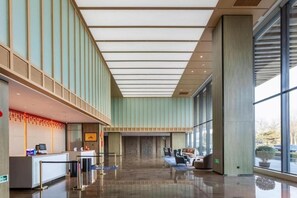 Un hall d’entrée spacieux avec un comptoir d’accueil, un espace salon et de grandes fenêtres.