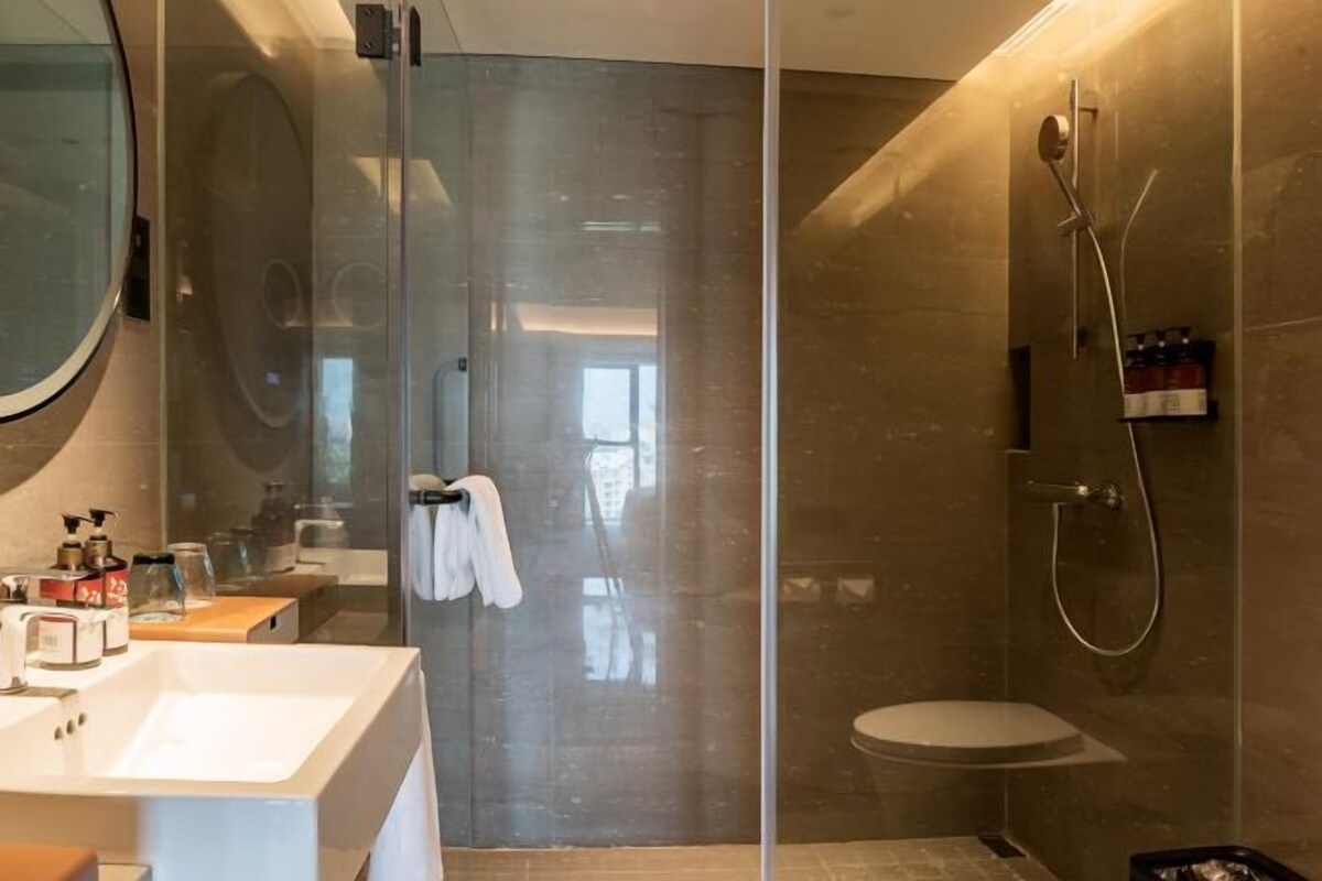 Une salle de bain moderne avec une douche à parois de verre, des toilettes et un lavabo équipé de produits de toilette.