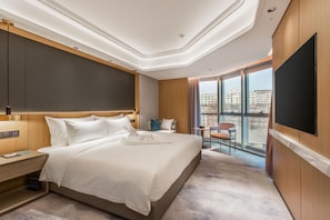 Une chambre d’hôtel avec un grand lit, un bureau, une chaise, une télévision et un balcon offrant une vue sur la ville.