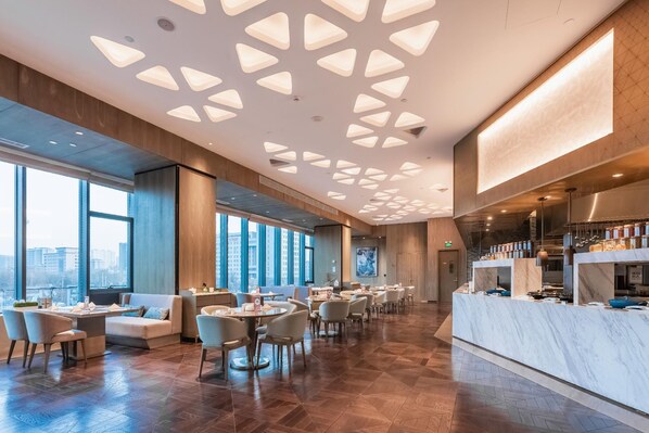 Un restaurant moderne avec un plafond haut, de grandes fenêtres et un comptoir en marbre.