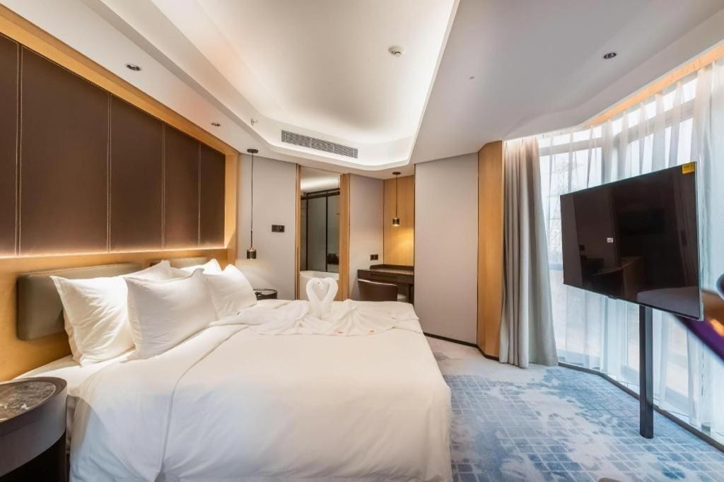 Une chambre d’hôtel avec un grand lit, un téléviseur à écran plat, un bureau et un miroir dans la salle de bain.