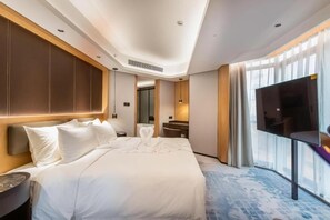 Une chambre d’hôtel avec un grand lit, un téléviseur à écran plat, un bureau et un miroir dans la salle de bain.