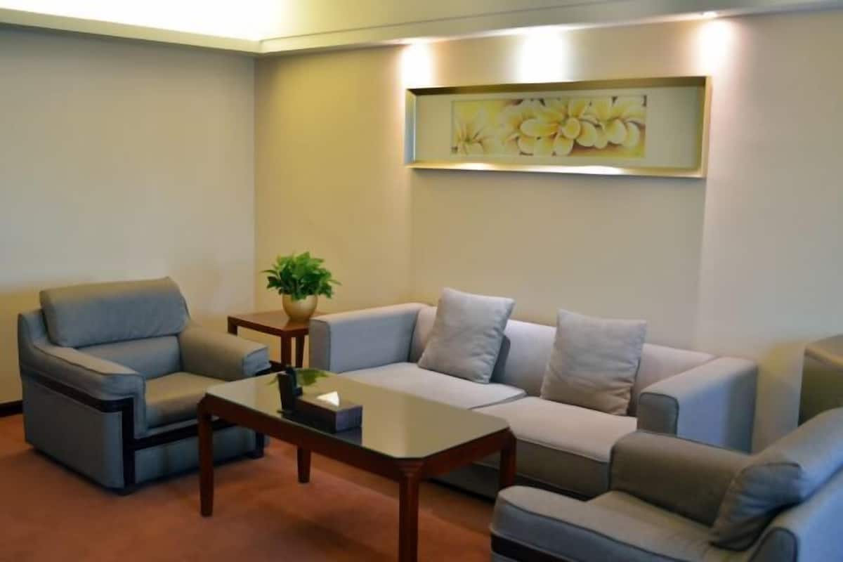 Ein modernes Wohnzimmer mit grauem Sofa, passendem Sessel, Couchtisch und einer Topfpflanze.