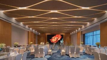 A conference room with a long table, chairs, and a stage with a large screen.