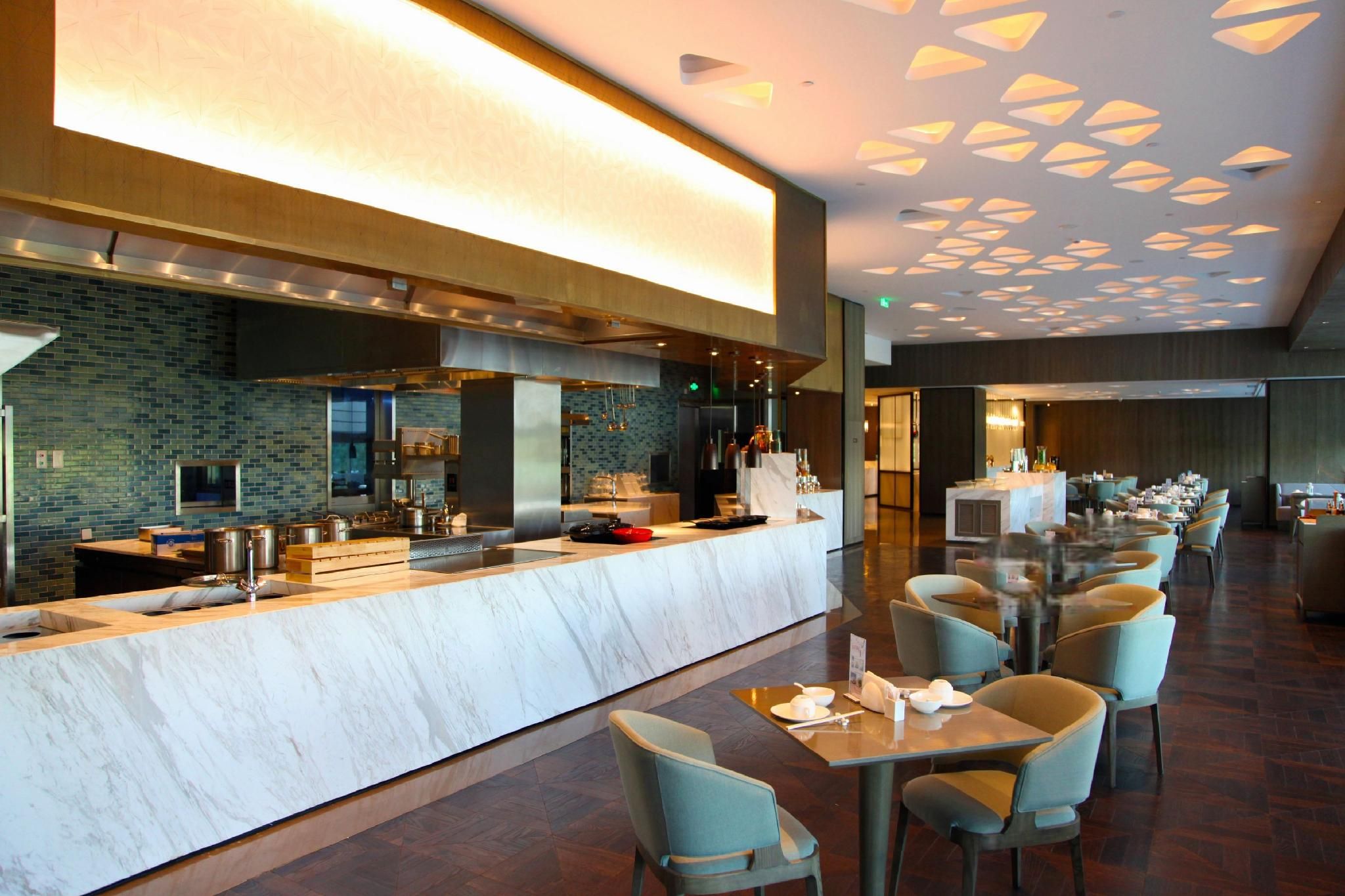 Un restaurante moderno con mostrador de mármol, zona de estar y techo con diseño.