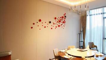 Un comedor moderno con una mesa redonda dispuesta para cuatro personas, una instalación de arte en la pared y un gran ventanal con cortinas.