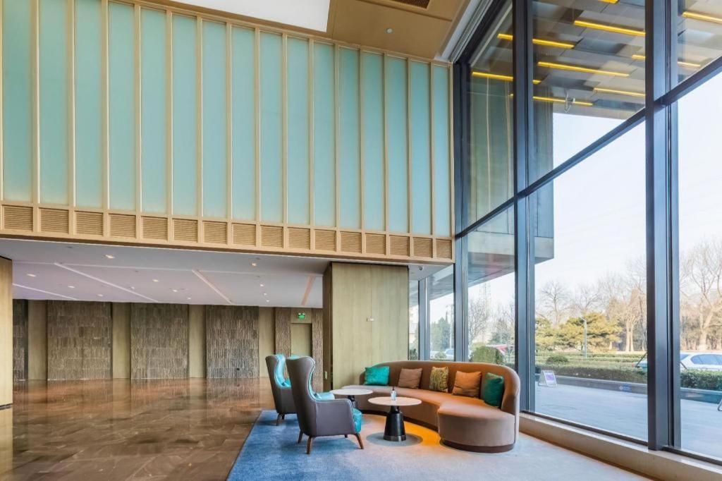 A modern lobby with a seating area, large windows, and a view of the outside.