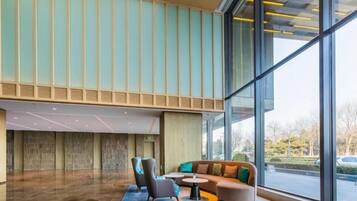 A modern lobby with a seating area, large windows, and a view of the outside.