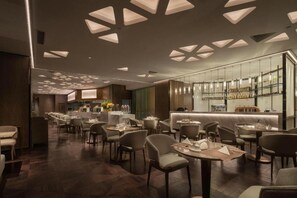 Ein modernes Restaurant mit einer langen Theke, mehreren Tischen und einer Bar.