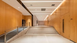 A modern hotel corridor with wooden walls, a glass railing, and a staircase leading to an upper floor. - RoyalRae YongXing Garden Hotel (Beijing)