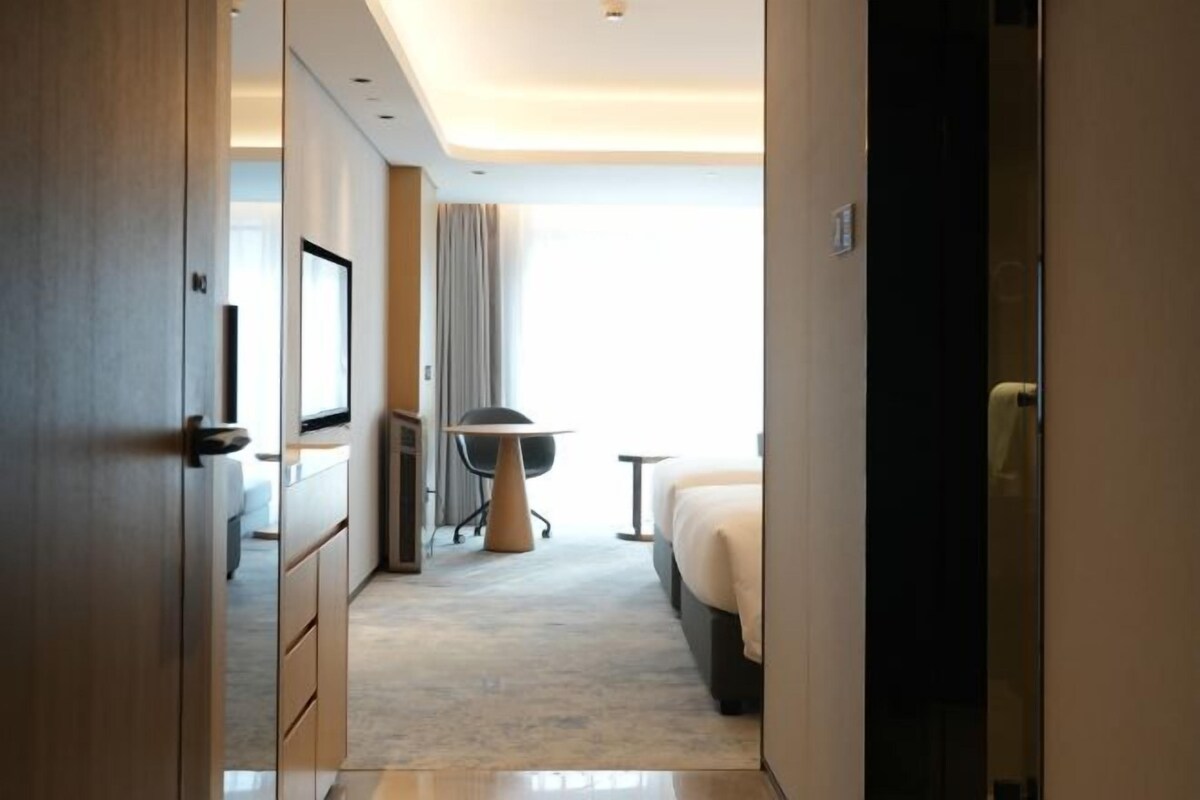 Una habitación de hotel con cama, escritorio, silla y ventana.