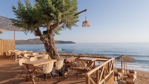 A wooden deck with wicker furniture and umbrellas overlooking the sea. - Eurohotel Theo Hotel (Chania)