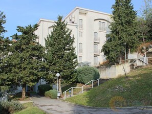 Un edifici de diversos pisos amb façana blanca, una escala a la dreta i un camí que condueix a l'entrada.