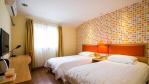 A hotel room with two beds, a desk with a computer, and a wall with a polka dot pattern. - Home Inn Jinsong (BEIJING)