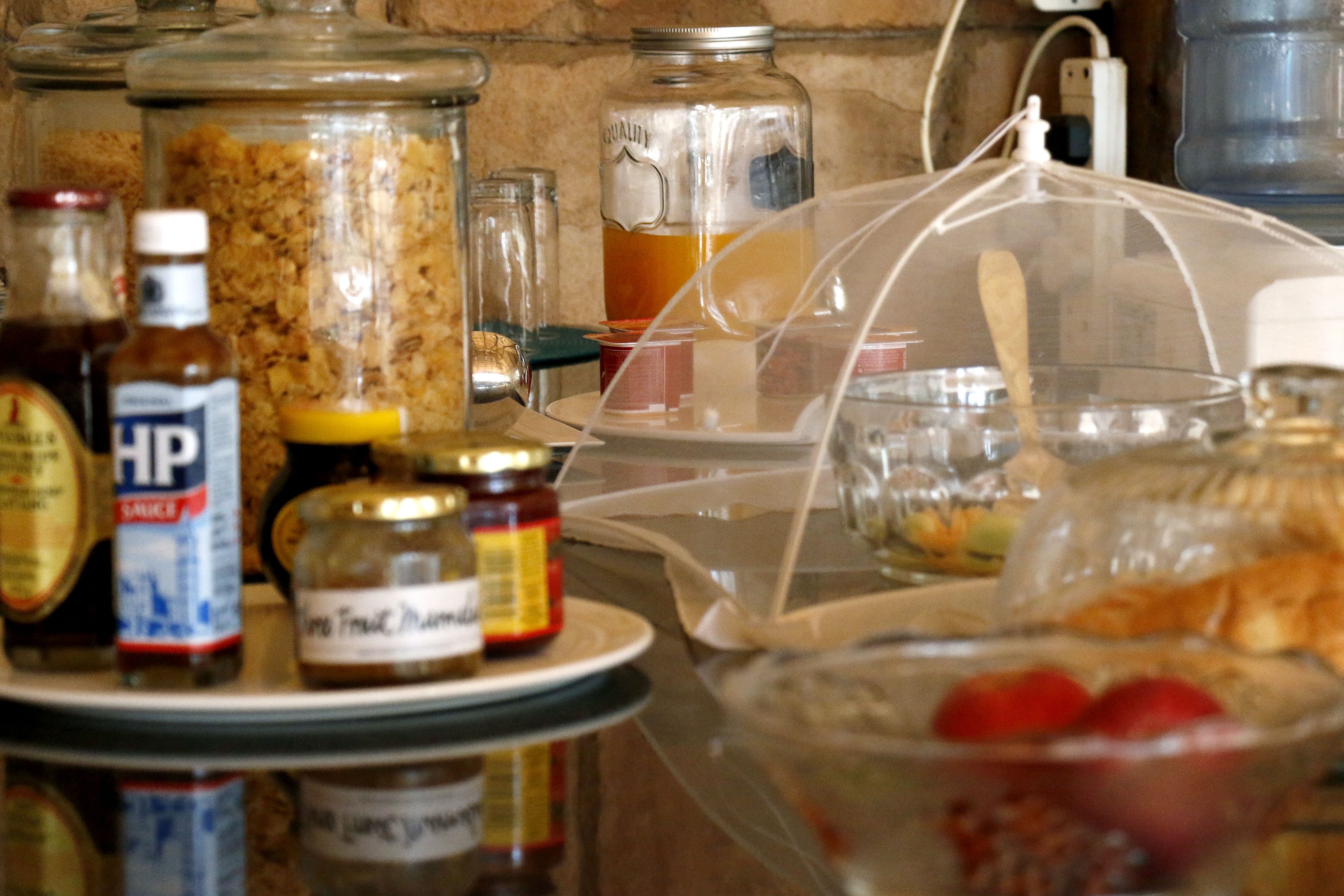 Una encimera de cocina con diversos alimentos y condimentos, incluyendo tarros de miel, mostaza y mermelada.