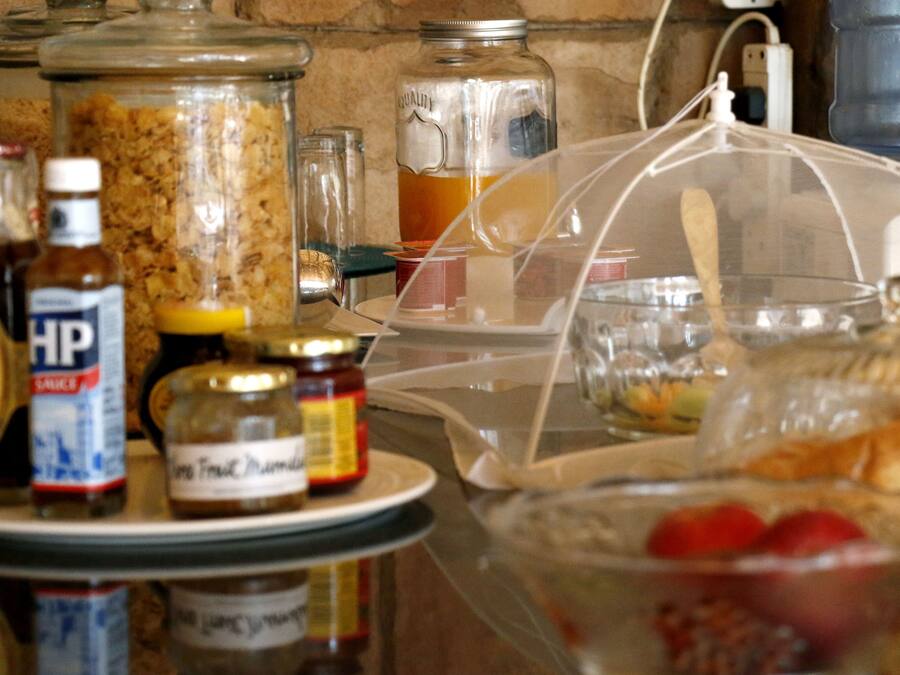 Una encimera de cocina con diversos alimentos y condimentos, incluyendo tarros de miel, mostaza y mermelada.
