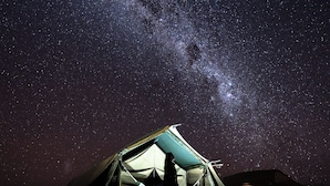 Tienda de campaña bajo un cielo estrellado con la Vía Láctea visible.