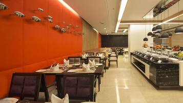 Un restaurante con una decoración moderna, paredes naranjas, mobiliario blanco y negro, y una zona de buffet.