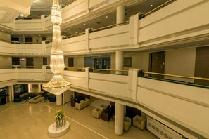 A multi-level hotel lobby with a large, ornate chandelier, multiple balconies, and a central seating area. - Howard Plaza The Fern, Agra (Agra)