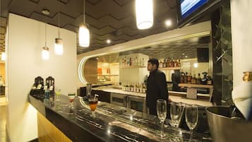Un espace bar doté d’un comptoir en marbre, de verres et de bouteilles.