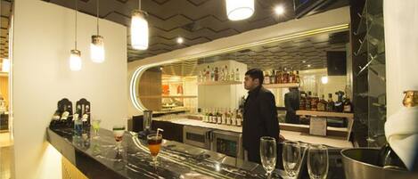 A bar area with a marble countertop, glasses, and bottles.