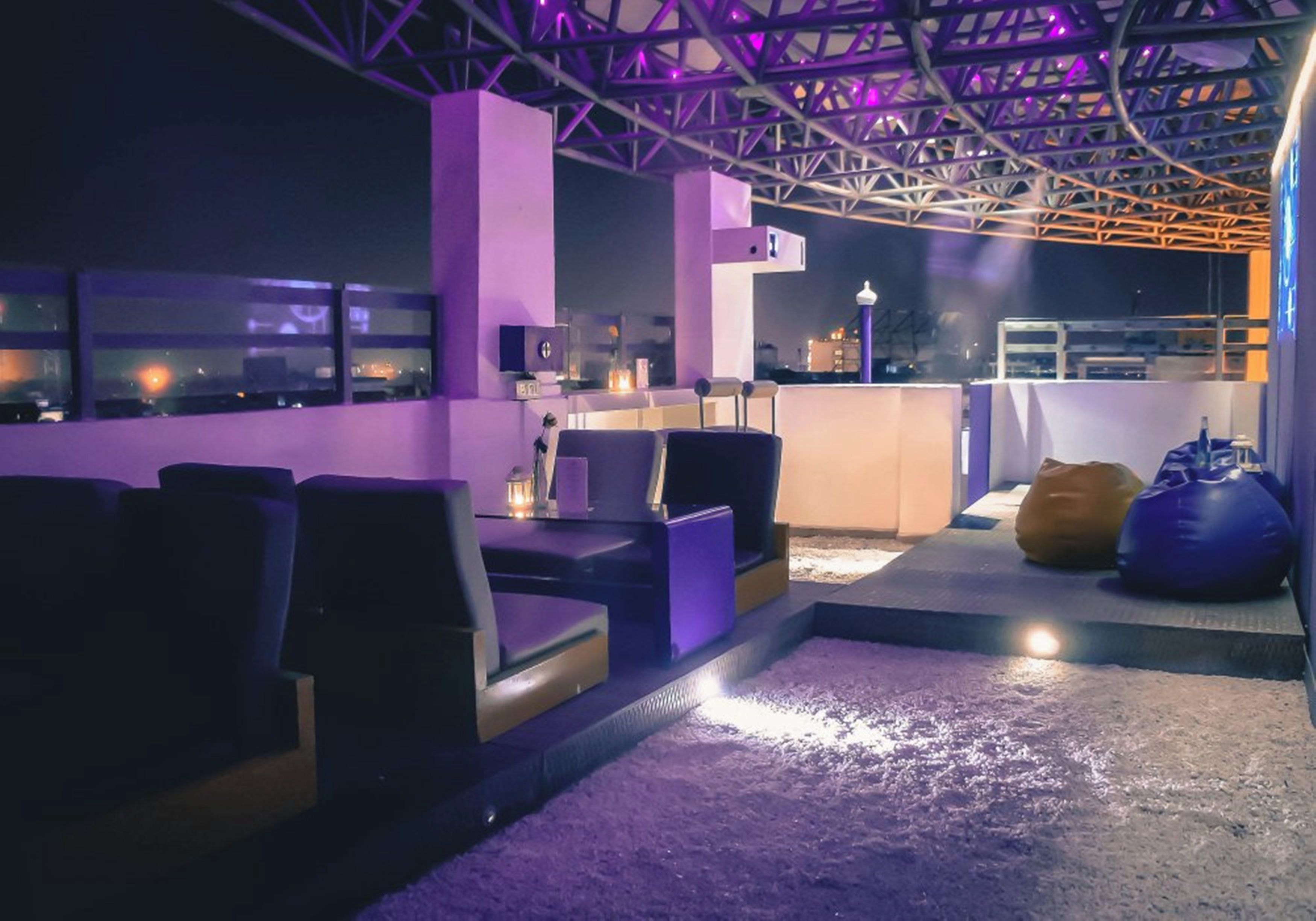 A rooftop bar with seating and a view of the cityscape.