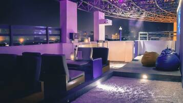 A rooftop bar with seating and a view of the cityscape.