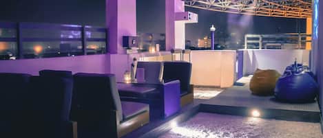 A rooftop bar with seating and a view of the cityscape.