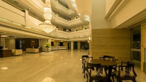 A spacious lobby with a chandelier, a reception desk, and a seating area with tables and chairs. - Howard Plaza The Fern, Agra (Agra)
