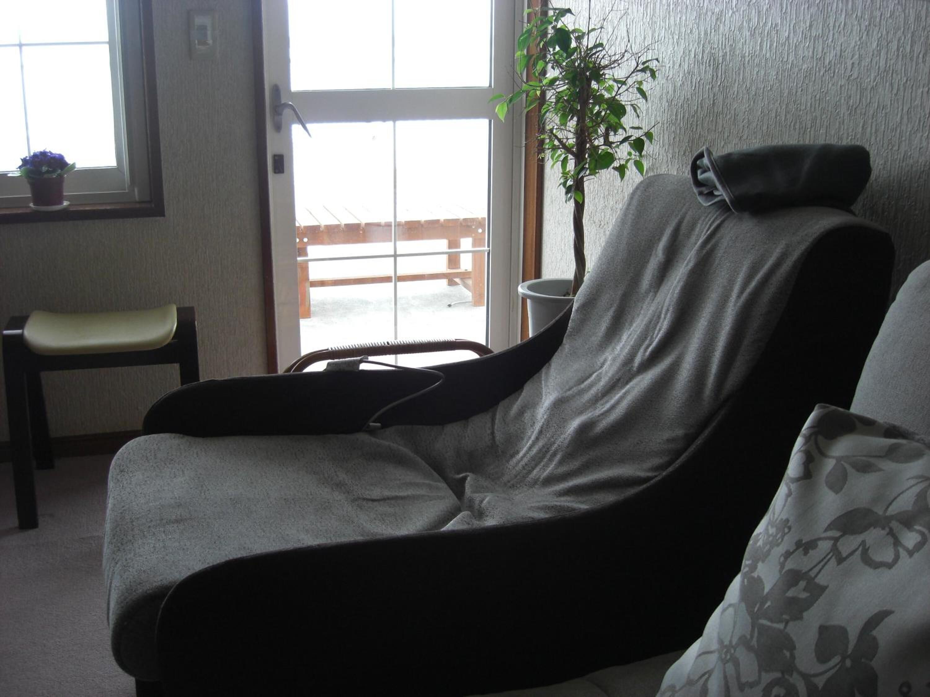 Una silla de masajes en una habitación con vista a una terraza de madera.