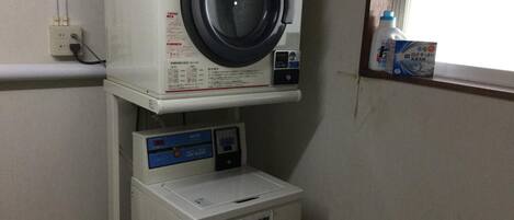 A compact laundry area with a washing machine, dryer, and a small trash bin.