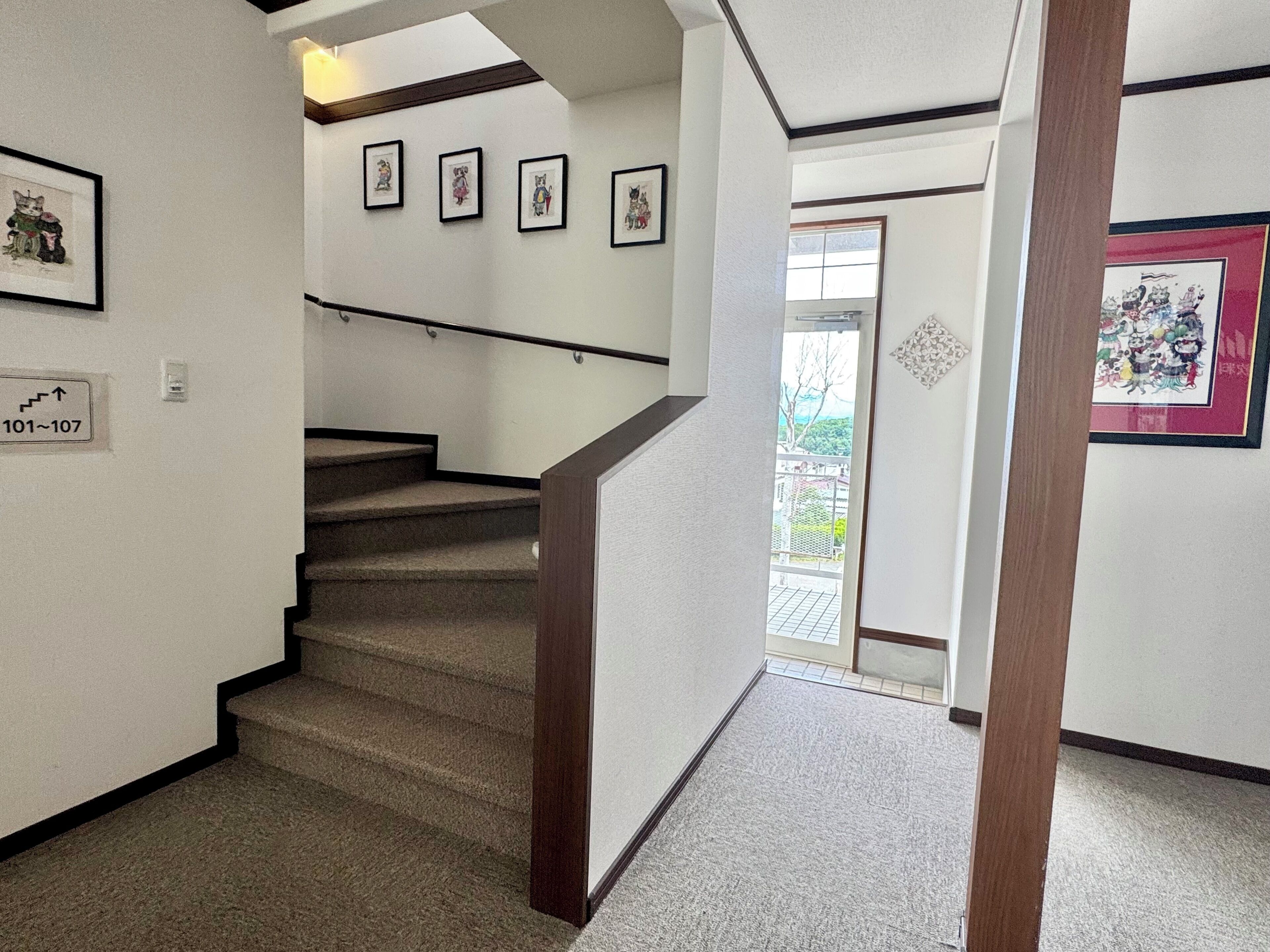 A staircase with a handrail, carpeted steps, and framed pictures on the walls.