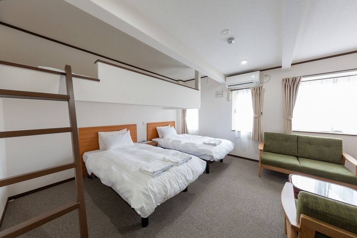 A hotel room with bunk beds, a sofa, and a small table.