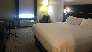 A hotel room with a large bed, a desk with a chair, a desk lamp, and a wall-mounted TV. - LMI Gulf Coast Homes, Port Charlotte (Port Charlotte)