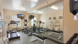 A gym with treadmills, elliptical machines, and a bench. - LMI Gulf Coast Homes, Port Charlotte (Port Charlotte)