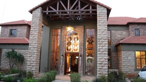 A stone building with a wooden porch and a large glass door. - Afrique Boutique Hotel Ruimsig (Roodepoort)