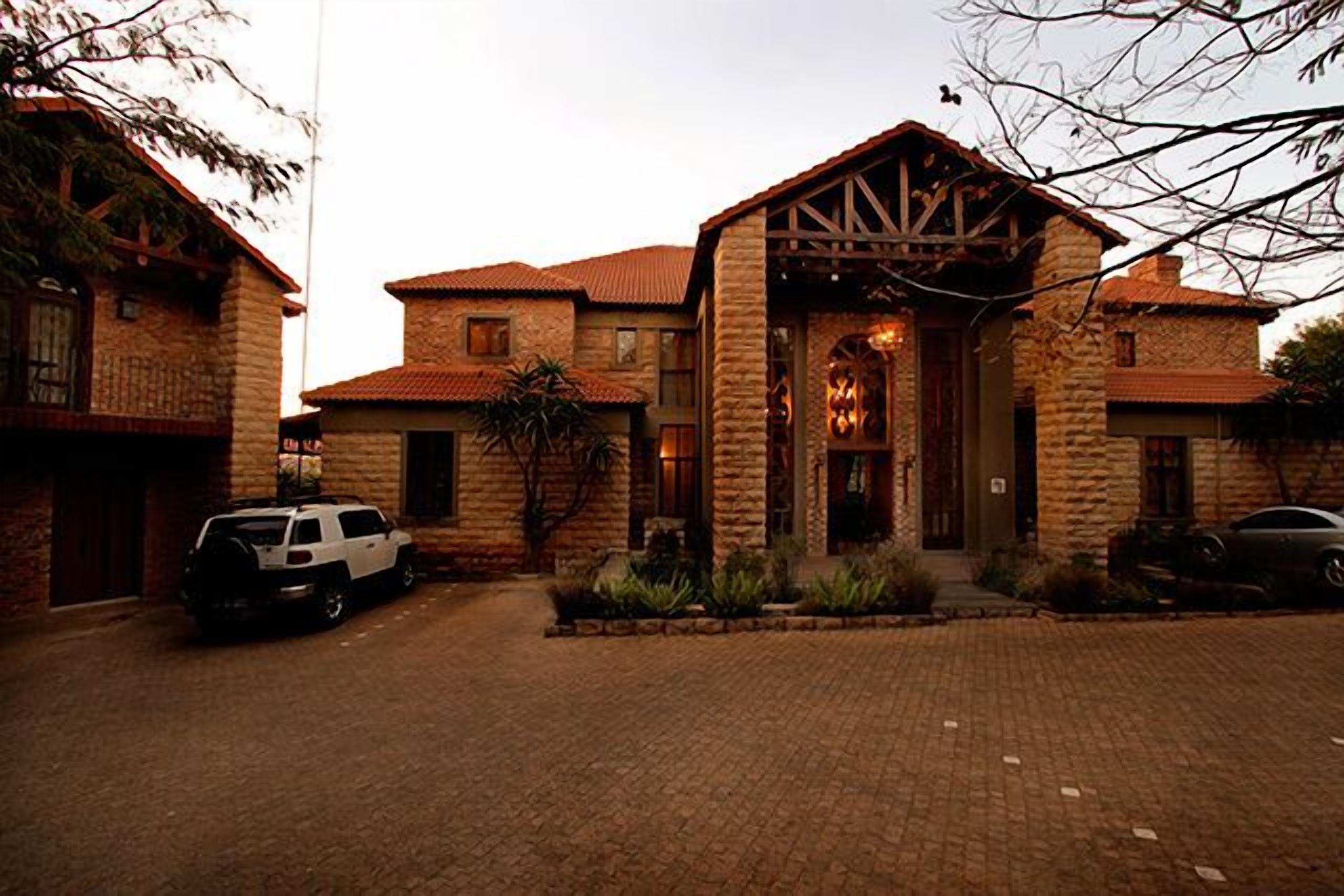 A stone building with a central entrance, two side wings, and a paved driveway.