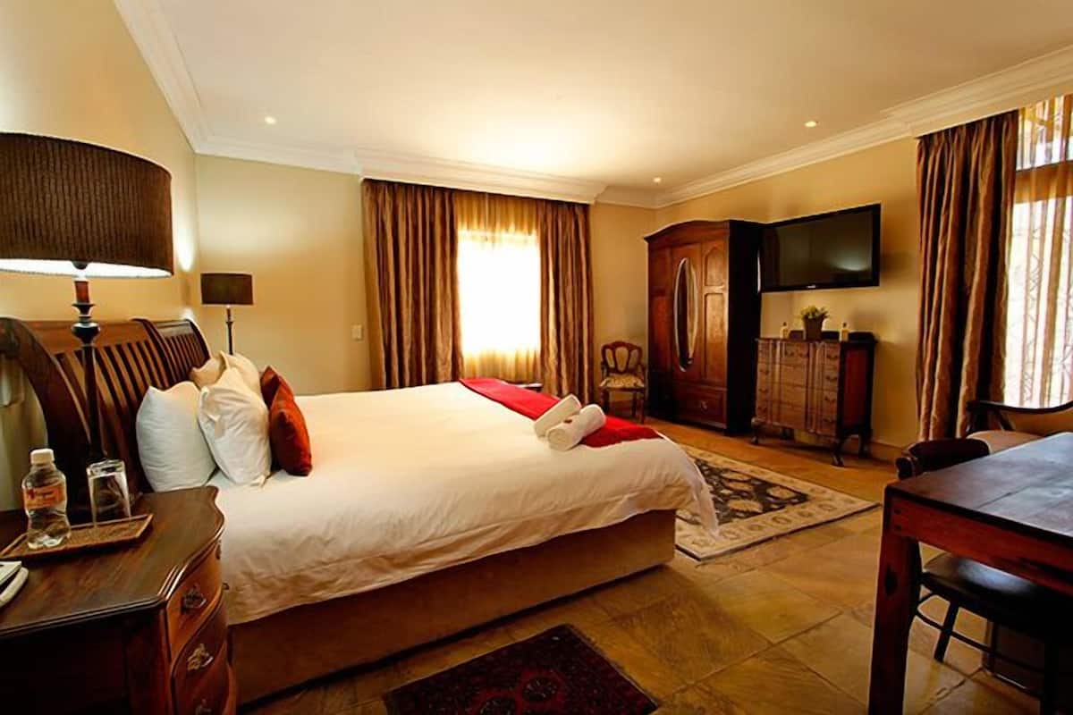Une chambre d’hôtel avec un grand lit, un bureau avec une lampe, une télévision et une armoire.