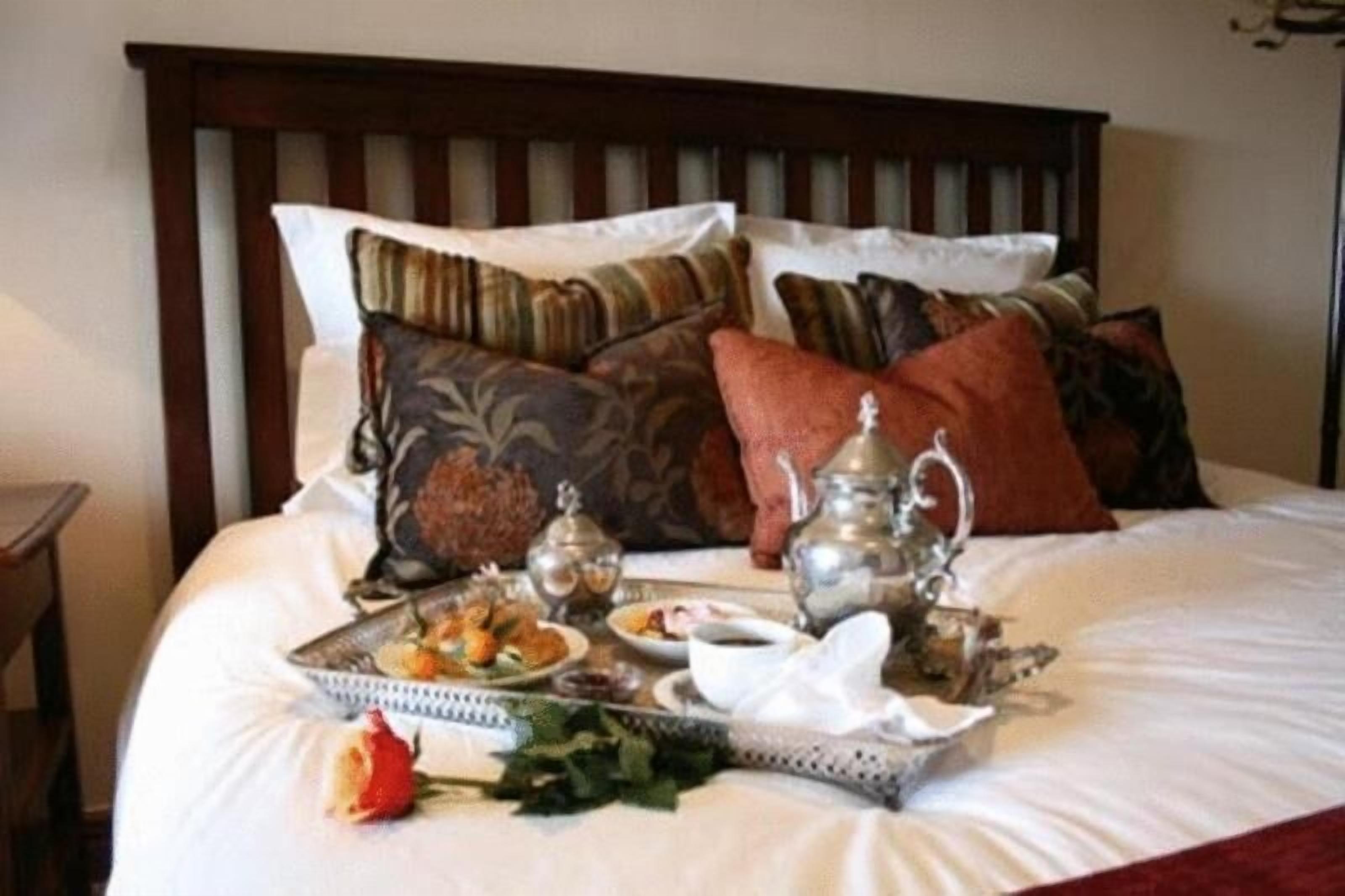 A neatly made bed with a tray of food and drinks, pillows, and a decorative item on the headboard.