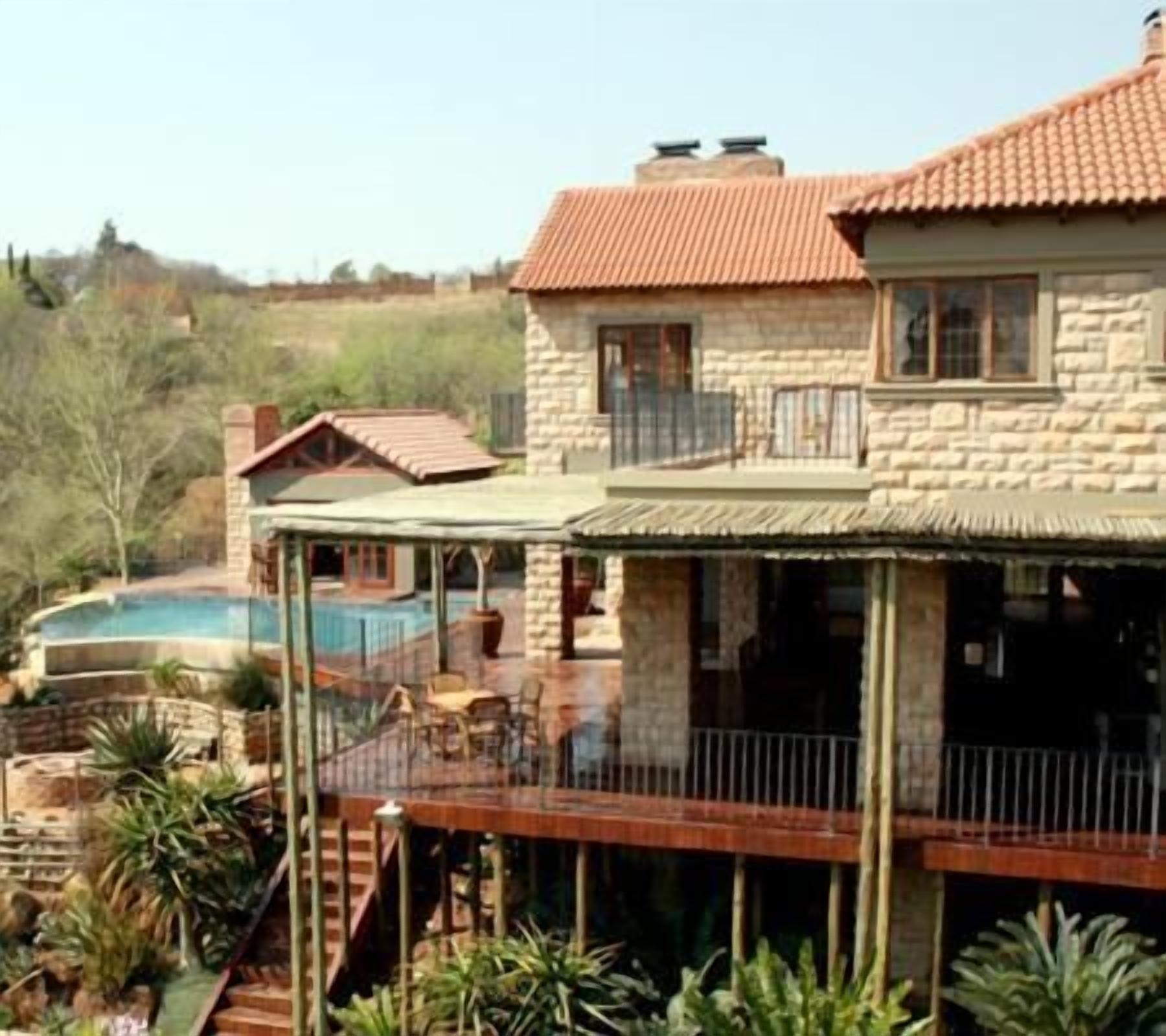 Uma casa de pedra com telhado de telhas vermelhas, varanda e piscina.