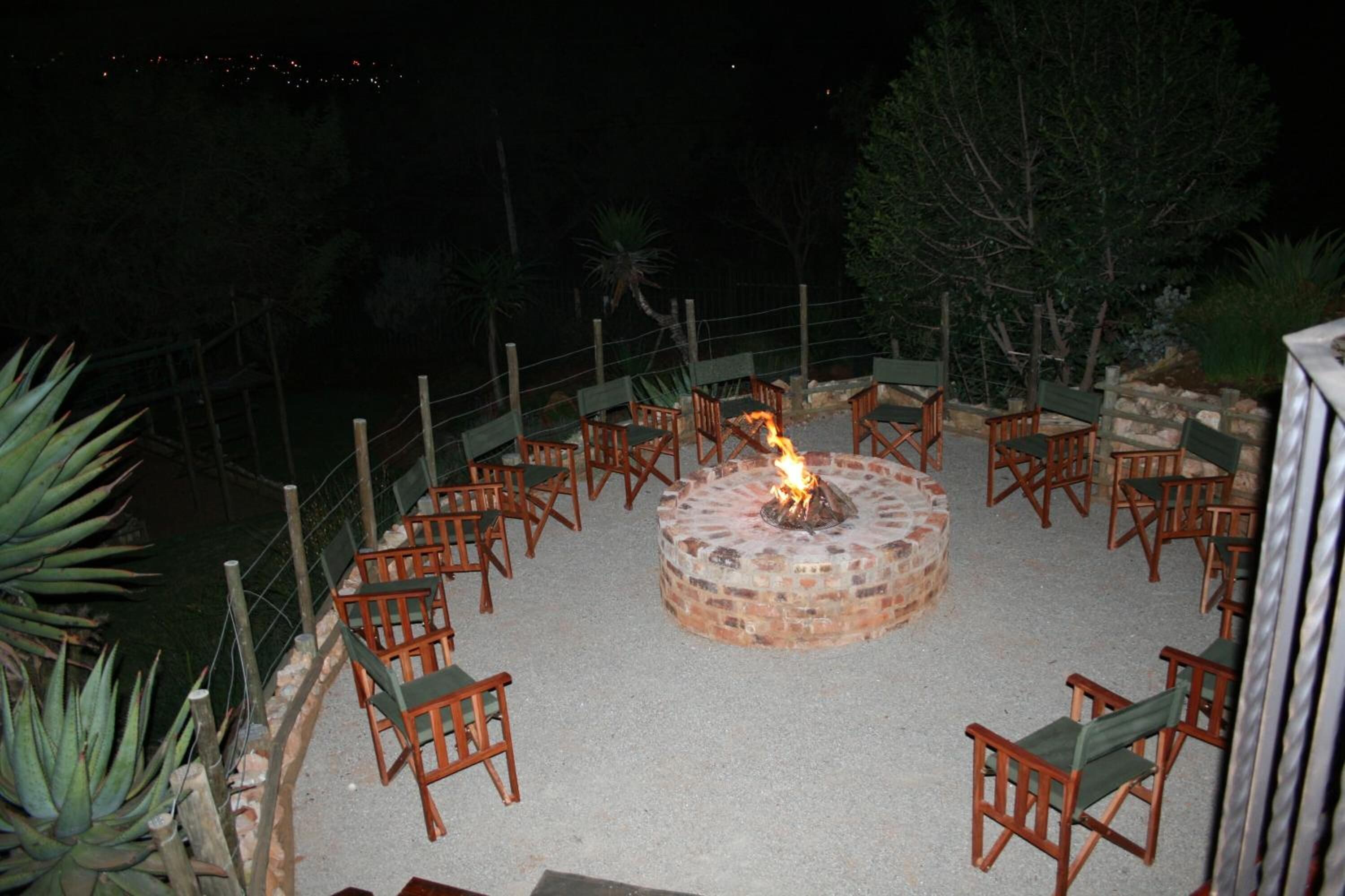 A circular outdoor seating area with a fire pit at the center, surrounded by wooden chairs.