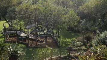 Un parque con una plataforma de observación circular, una estructura de madera y un área cercada con árboles.