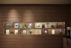 Eine Wand mit mehreren Regalen, auf denen Bücher und kleine Topfpflanzen stehen.